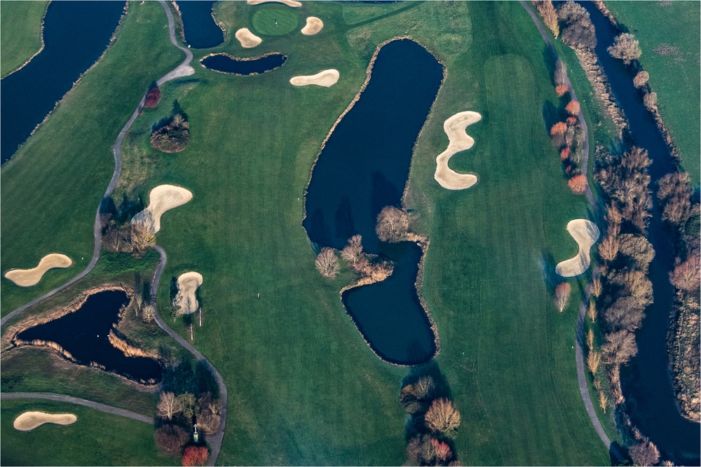 lege golfbaan met watertjes gezien van bovenaf