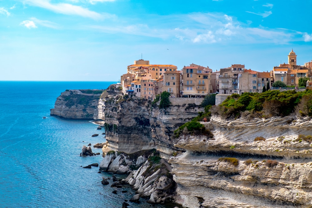 kliffen met huizen aan zee en in de verte een kerktoren in Bonifacio, Zuid-Corsica